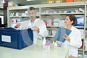 Male and female pharmacists maintaining checklist at counter in pharmacy