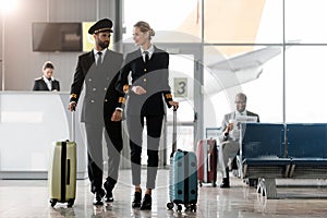 male and female pilots walking by airport lobby