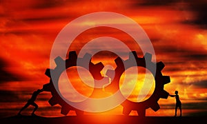 Male and Female Pushing Gears At Sunset Orange sky. Business Persons Collaborate Together to Connect The Cogwheels.