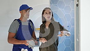 Male and female repairers planning works in bathroom, making pointing finger gesture.