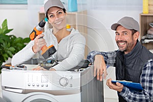 male and female repairers stanging near washing machine photo