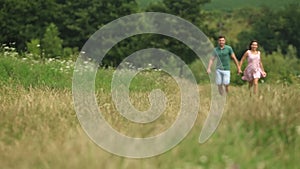 Male and female run togeter in field. Romantic atmosphere