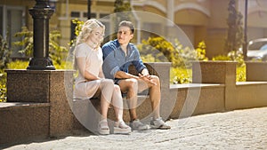 Male and female sitting on bench next to each other, feeling awkward, first date