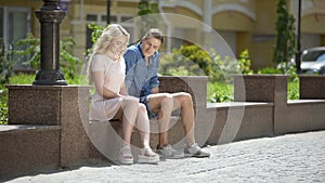 Male and female sitting on bench next to each other, feeling awkward, first date