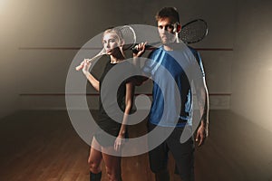 Male and female squash game players with rackets