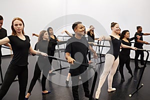 Male And Female Students At Performing Arts School Rehearsing Ballet In Dance Studio Using Barre