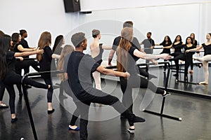 Male And Female Students At Performing Arts School Rehearsing Ballet In Dance Studio Using Barre