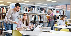 Male and female students preparing for exam together in library