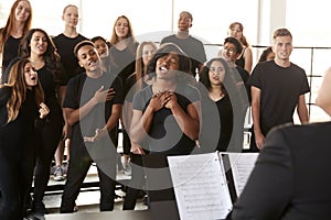 Male And Female Students Singing In Choir With Teacher At Performing Arts School photo