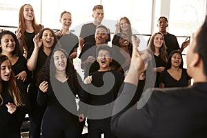 Male And Female Students Singing In Choir With Teacher At Performing Arts School photo