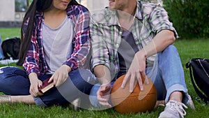 Male and female students sitting on lawn closely, having conversation, flirting