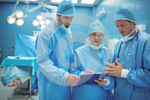 Male and female surgeon discussing over clipboard in operation theater