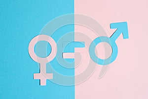 Male and female symbols cut out of paper and an equal sign on a pink and blue paper background. the concept of gender equality
