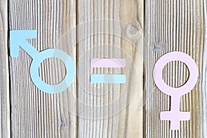 Male and female symbols cut out of paper and an equal sign on a wooden background. the concept of gender equality