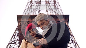 Male and female tourists searching destination in Paris on map in mobile app