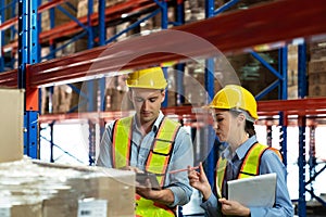 Male and Female warehouse workers discussing shipping schedule. Logistic and business export concept