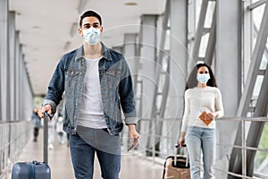 Male And Female Wearing Face Masks While Walking With Luggage At Airport