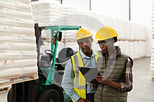 Male and female worker discussing over clipboard in warehouse