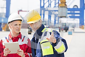 Male and female workers discussing in shipping yard