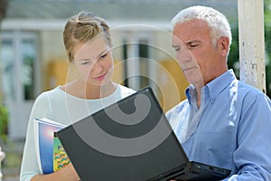 male and female workers stood outdoors looking at laptop