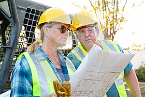 Male and Female Workers With Technical Blueprints Talking