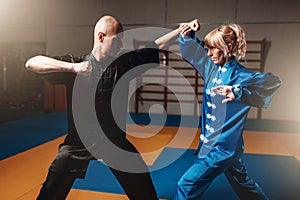 Male and female wushu fighters exercises indoor