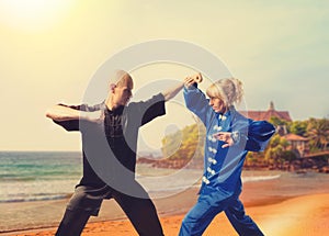 Male and female wushu fighters training on coast