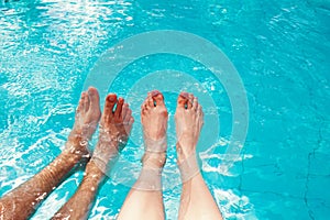 Male and femle feet in swimming pool. R