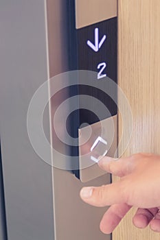 Male finger pressing down arrow elevator button