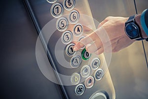 Male finger pressing the first floor button in the elevator