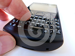 Male finger typing on vintage button type cell phone qwerty keyboard