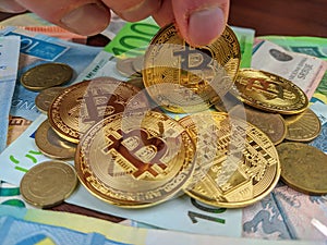 Male fingers holding golden bitcoin coin as a preferable choice of cryptocurrency and payment in the future and a smart investment