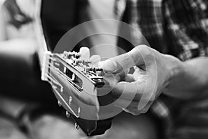 Male fingers tuning guitar strings. Black and white concept. Close-up