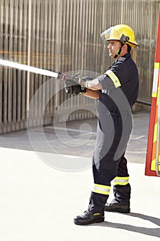 Male firefighter, spray water and emergency worker with helmet, uniform and brave to stop inferno. Fireman, fire hose