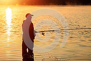Male fisherman at dawn on the lake catches a fishing rod. Fishing hobby vacation concept. Copy space