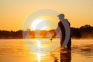 Male fisherman at dawn on the lake catches a fishing rod. Fishing hobby vacation concept. Copy space