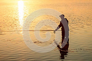 Male fisherman at dawn on the lake catches a fishing rod. Fishing hobby vacation concept. Copy space