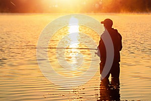 Male fisherman at dawn on the lake catches a fishing rod. Fishing hobby vacation concept. Copy space