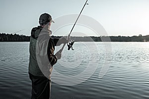 Male fisherman at dawn on the lake catches a fishing rod. Fishing hobby vacation concept. Copy space