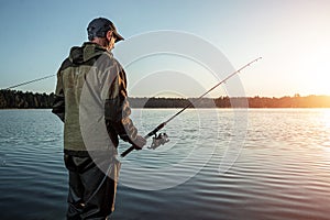 Male fisherman at dawn on the lake catches a fishing rod. Fishing hobby vacation concept. Copy space