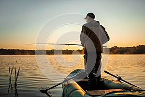 Male fisherman at dawn on the lake catches a fishing rod. Fishing hobby vacation concept. Copy space