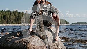 male fisherman holds a large fish pike caught in his hands