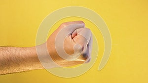 Male fist. gesture threatens and aggression on isolated yellow background