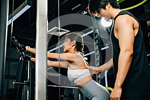Male fitness coach teaching a woman how to use a pulldown cable machine