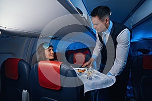 Male flight attendant giving airline meal to woman