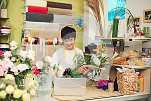 Male florist in flower shop. Man in apron is cutting stems and preparing roses for a bouquet. Owner of the flower shop, doing