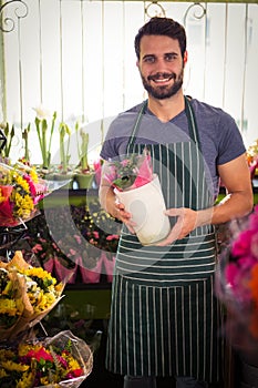 Male florist holding pot plant at his flower shop