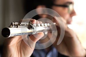 A male flutist playing, indoors.