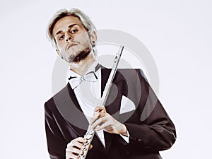 Male flutist wearing tailcoat holds flute