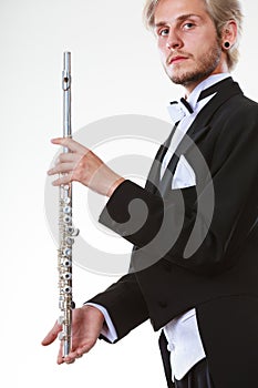 Male flutist wearing tailcoat holds flute